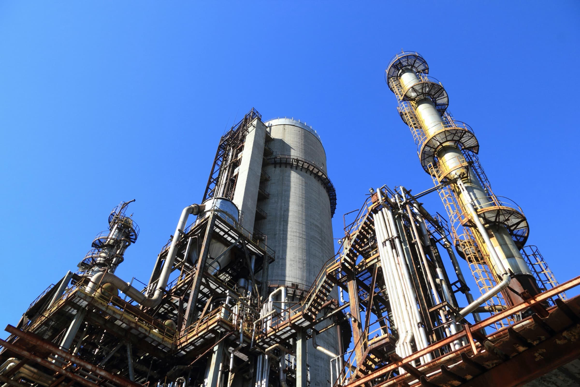 Industrieanlage mit Kolonnen und Schornsteinen vor blauem Himmel